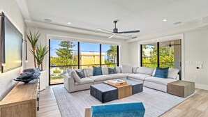 A modern living room with a sectional sofa, a coffee table, and a blue chair. - Sunset Reflections | LUXURY Home, Private Pool, Spa, Rooftop, Game Room, and MORE! (Anna Maria)