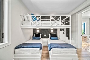A modern bedroom with two beds, a loft bed, and a small desk area. - Sunset Reflections | LUXURY Home, Private Pool, Spa, Rooftop, Game Room, and MORE! (Anna Maria)