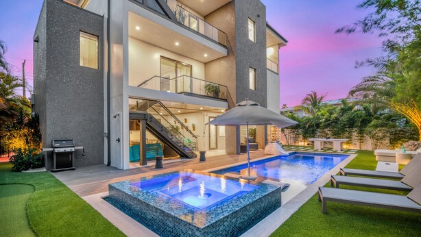 A modern two-story house with a swimming pool, outdoor furniture, and a well-maintained lawn. - Sunset Reflections | LUXURY Home, Private Pool, Spa, Rooftop, Game Room, and MORE! (Anna Maria)