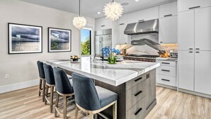 A modern kitchen with a large island, bar stools, and pendant lights. - Sunset Reflections | LUXURY Home, Private Pool, Spa, Rooftop, Game Room, and MORE! (Anna Maria)