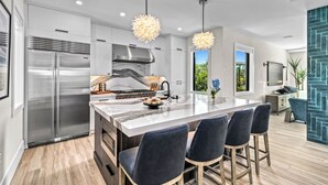 A modern kitchen with a large island, stainless steel appliances, and pendant lighting. - Sunset Reflections | LUXURY Home, Private Pool, Spa, Rooftop, Game Room, and MORE! (Anna Maria)