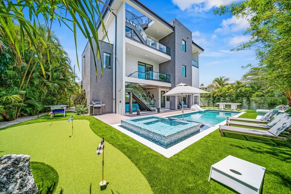 A modern two-story house with a swimming pool, a covered patio, and a well-maintained lawn. - Sunset Reflections | LUXURY Home, Private Pool, Spa, Rooftop, Game Room, and MORE! (Anna Maria)