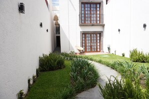 Enter a serene courtyard with a beautifully maintained lawn and lush plants, surrounded by clean lines and a peaceful atmosphere.