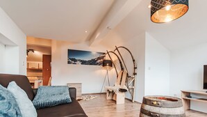 Ein modernes Wohnzimmer mit einem dunklen Sofa, einem Holzbottich und einem rustikalen Sessel.