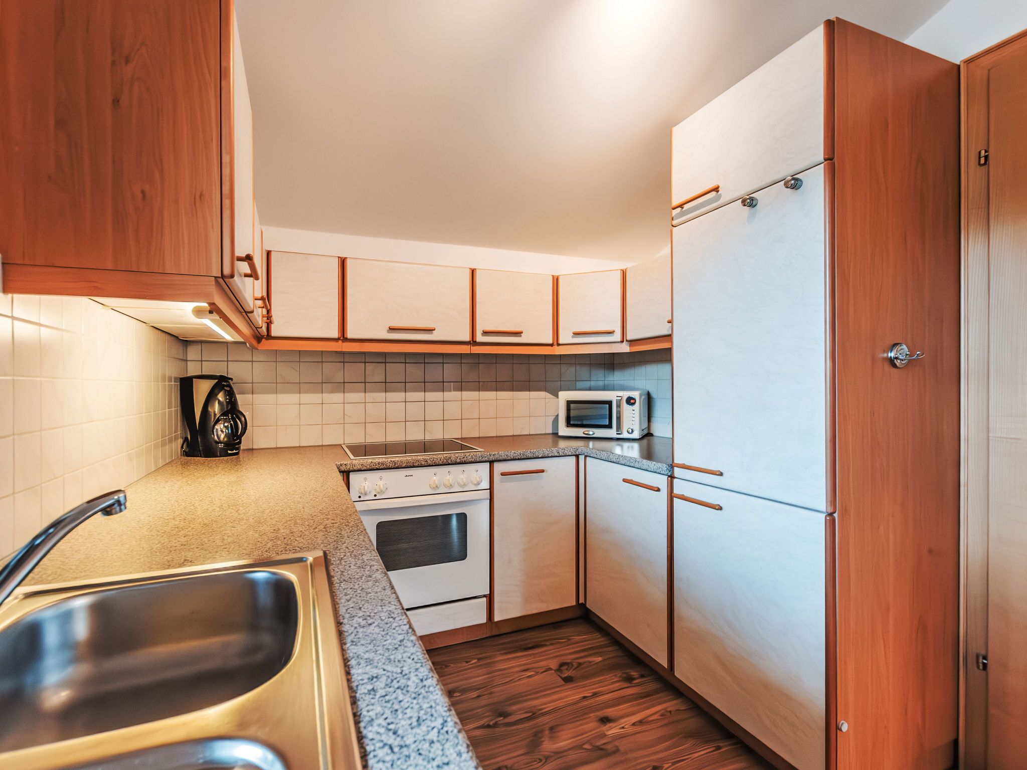 Una cocina compacta con gabinetes blancos, un microondas, una estufa y un lavamanos.