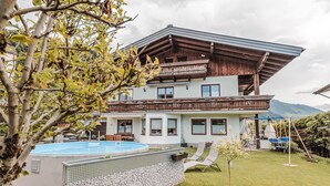 Eine zweistöckige Chalet mit Schwimmbad, Balkon und Garten.