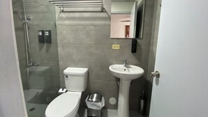 A modern bathroom with a toilet, sink, and glass shower enclosure.
