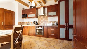 Una cocina moderna con gabinetes de madera, una campana extractora de acero inoxidable y un salpicadero de azulejos.