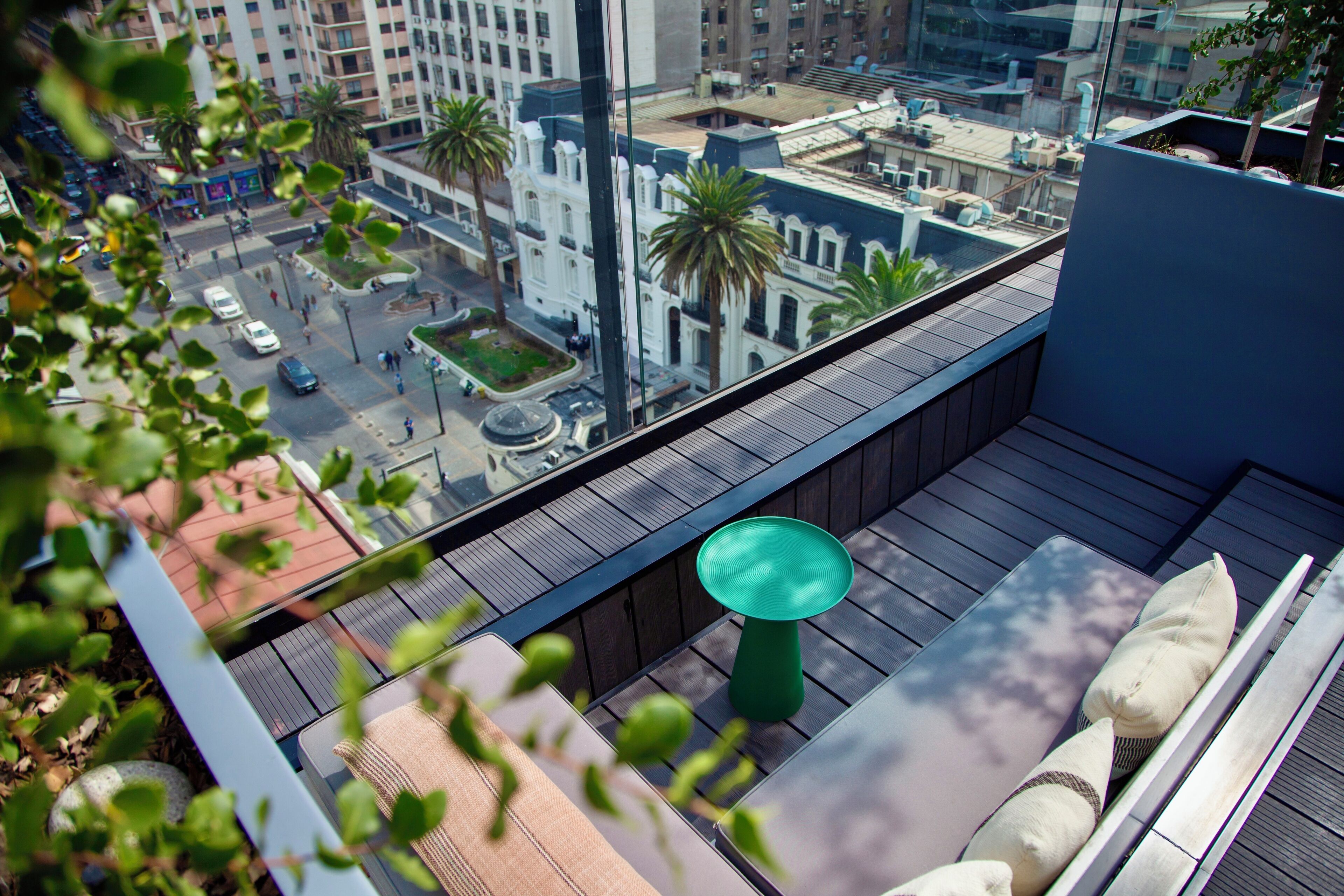 A rooftop terrace with a view of a cityscape, including palm trees and buildings.