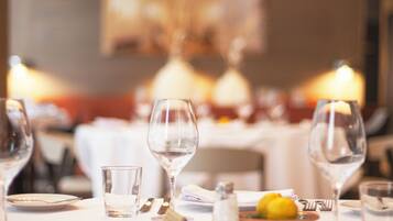 A dining table set with wine glasses, plates, and a small bowl of lemons.