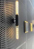 A wall with a perforated metal design and two plaques.