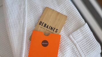 Une carte en bois portant l’inscription « DEBAINES HOTEL EL SANTIAGO », posée sur une serviette blanche.