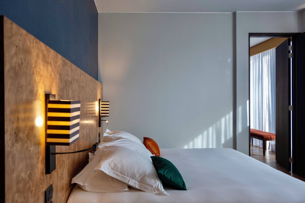 Habitación de hotel moderna con una cama grande, cabecera de madera y vistas al exterior.