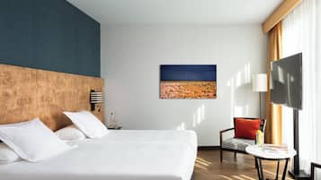 A hotel room with a large bed, a flat-screen TV, a small table, and a chair.