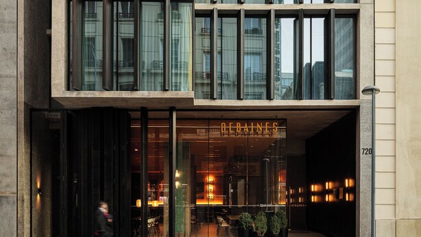 Un edificio moderno con fachada de vidrio y un cartel que dice "DEBAINES".