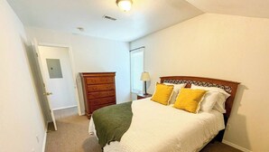 Ein Schlafzimmer mit Bett, Kommode und Tür.