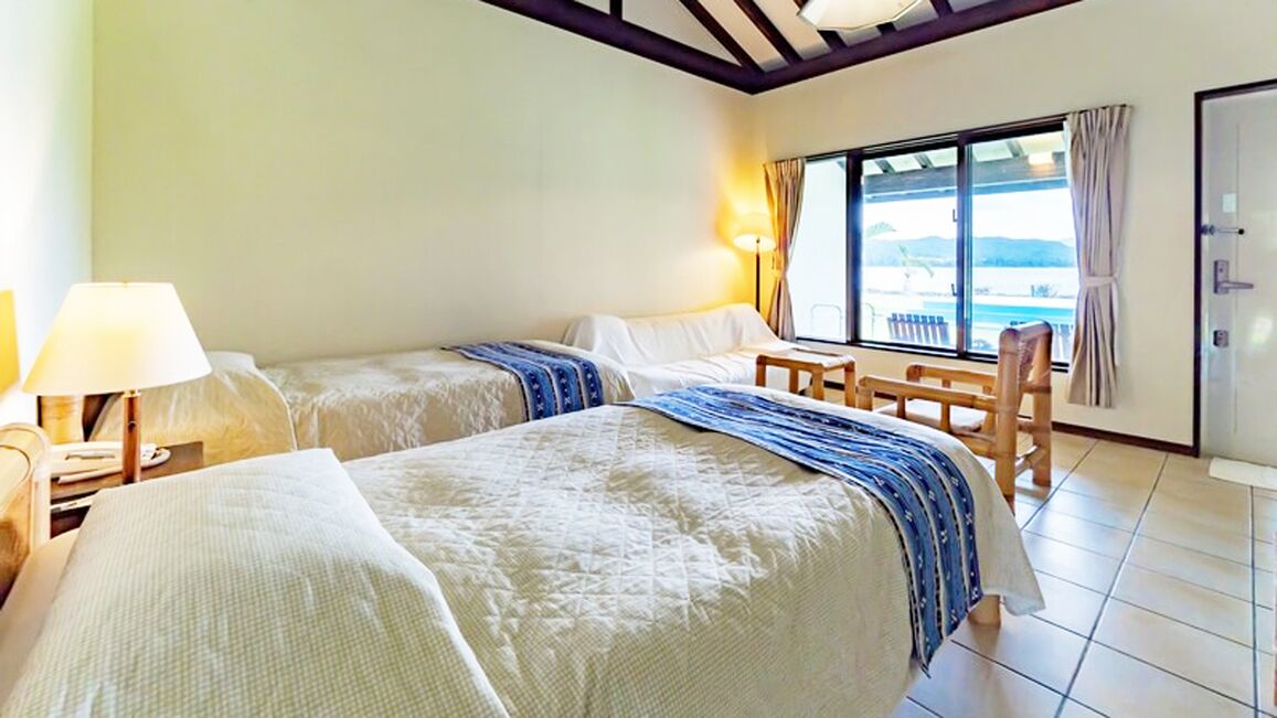 Une chambre d’hôtel avec deux lits, une fenêtre donnant sur un beau paysage, une table et une chaise.