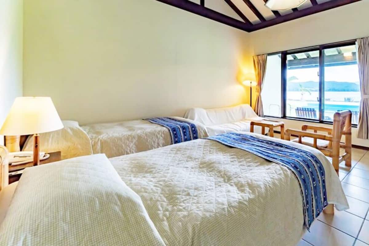 Een hotelkamer met twee bedden, een raam met uitzicht, een tafel en een stoel.