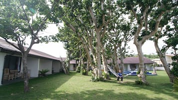 Un barrio residencial con césped, árboles y una hamaca.