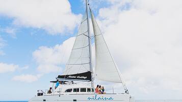 A white sailboat with the name "Nina" on its side, sailing on clear blue water.