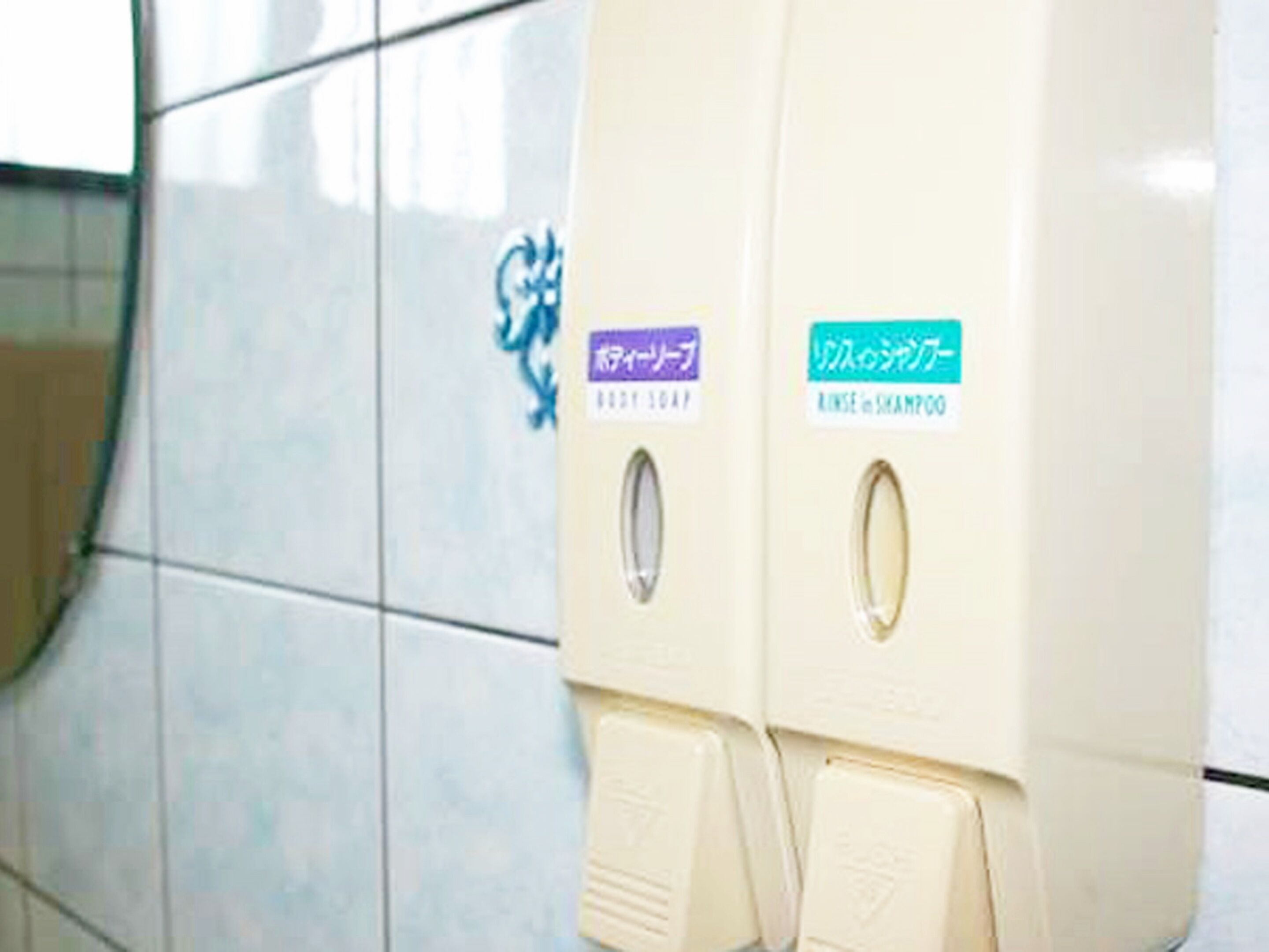 A restroom with two dispensers labeled for soap and shampoo.