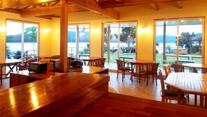 A wooden interior with large windows offering a view of a lake and hills. - VILLA  UNARIZAKI (Taketomi)