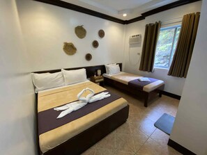 A hotel room with two beds, a window with curtains, a wall-mounted air conditioner, and decorative wall art. - Oceana Bay Coron (Coron)