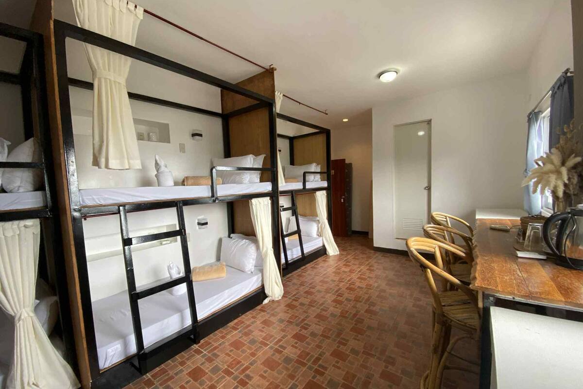 A dormitory room with bunk beds, a small desk, and a chair.