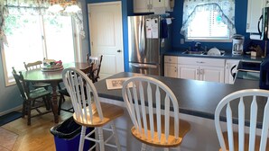 A kitchen with a central island, white cabinets, a stainless steel refrigerator, and a ceiling fan. - Lake Winnebago Water Front! Fishing! Boating! Quiet Bay! EAA! (Oshkosh)