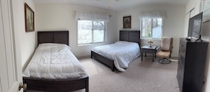 A bedroom with two beds, a desk, a chair, and a dresser.