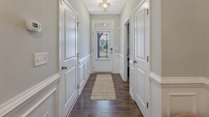A hallway with white doors, a thermostat, and a ceiling light. - Where Relaxation Meets Home, KING Suite RETREAT, 14 MINS to RDU Airport, POOL (Morrisville)