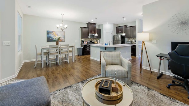 A modern kitchen with dark cabinets, a central island, and a dining area with a white table and chairs. - Where Relaxation Meets Home, KING Suite RETREAT, 14 MINS to RDU Airport, POOL (Morrisville)