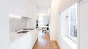 Une cuisine moderne avec des meubles blancs, un plancher en bois et une fenêtre qui laisse entrer la lumière naturelle.