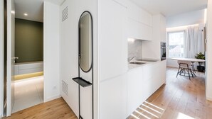 Une cuisine moderne avec des meubles blancs, un four encastré et un coin repas comprenant une table et des chaises.