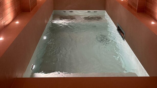 Una spa con vasca idromassaggio rettangolare, pareti in mattoni ad arco e illuminazione incassata.