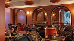 A restaurant with patterned seating, round tables, and arched mirrors.