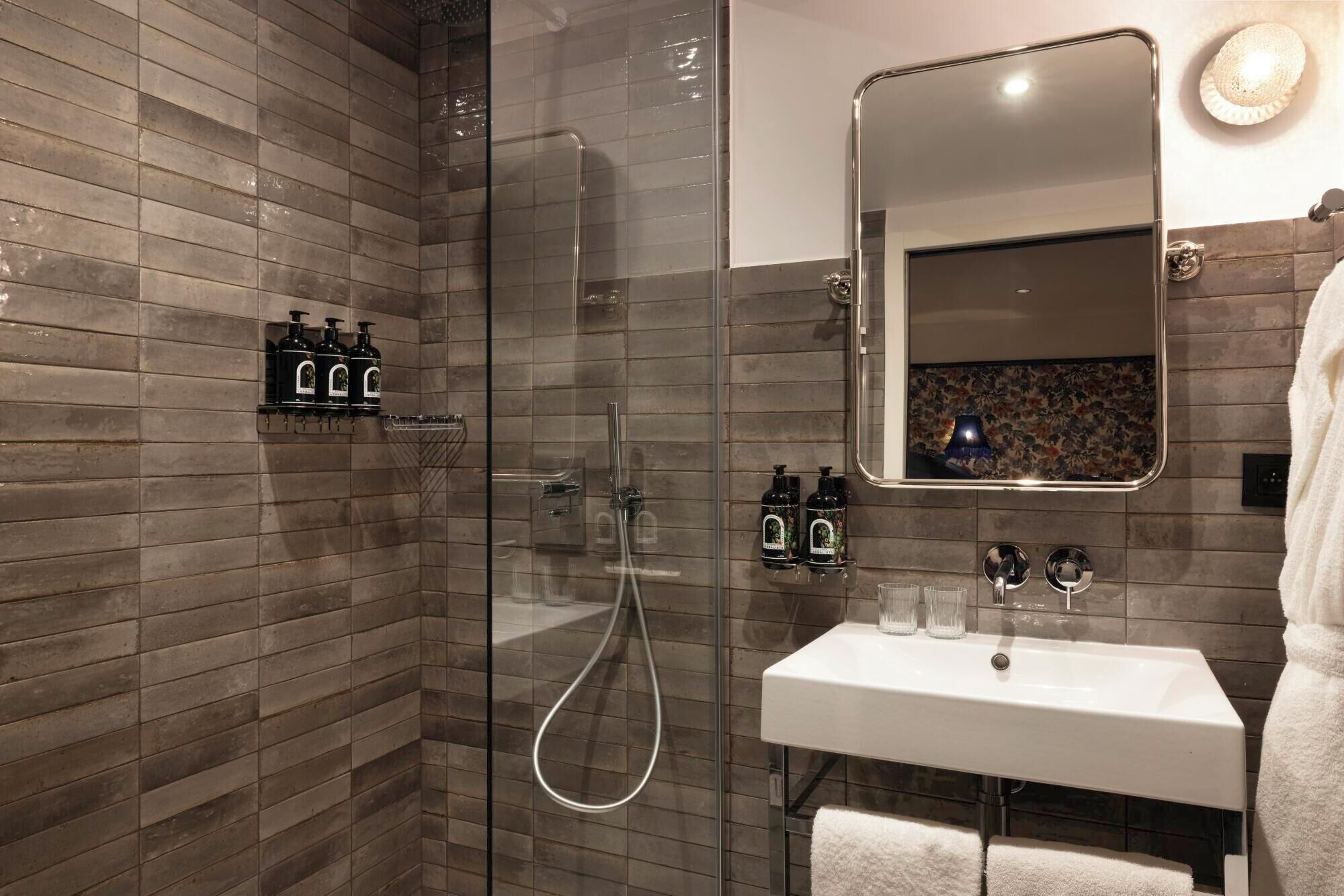 Un bagno moderno con cabina doccia in vetro, lavandino bianco e specchio con decorazione floreale.