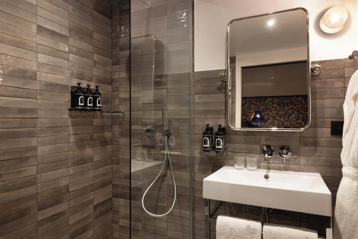 Un bagno moderno con cabina doccia in vetro, lavandino bianco e specchio con decorazione floreale.