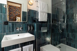 A modern bathroom with a white sink, a glass-enclosed shower, and a mirror with a floral pattern.