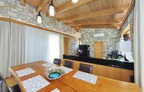 A dining area with a stone wall, wooden ceiling, and a black countertop. - Lovely home in Bast with sauna (Bast)