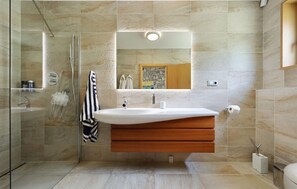 A modern bathroom with a glass shower enclosure, a vanity with a white sink, and a wooden cabinet below. - Lovely home in Bast with sauna (Bast)