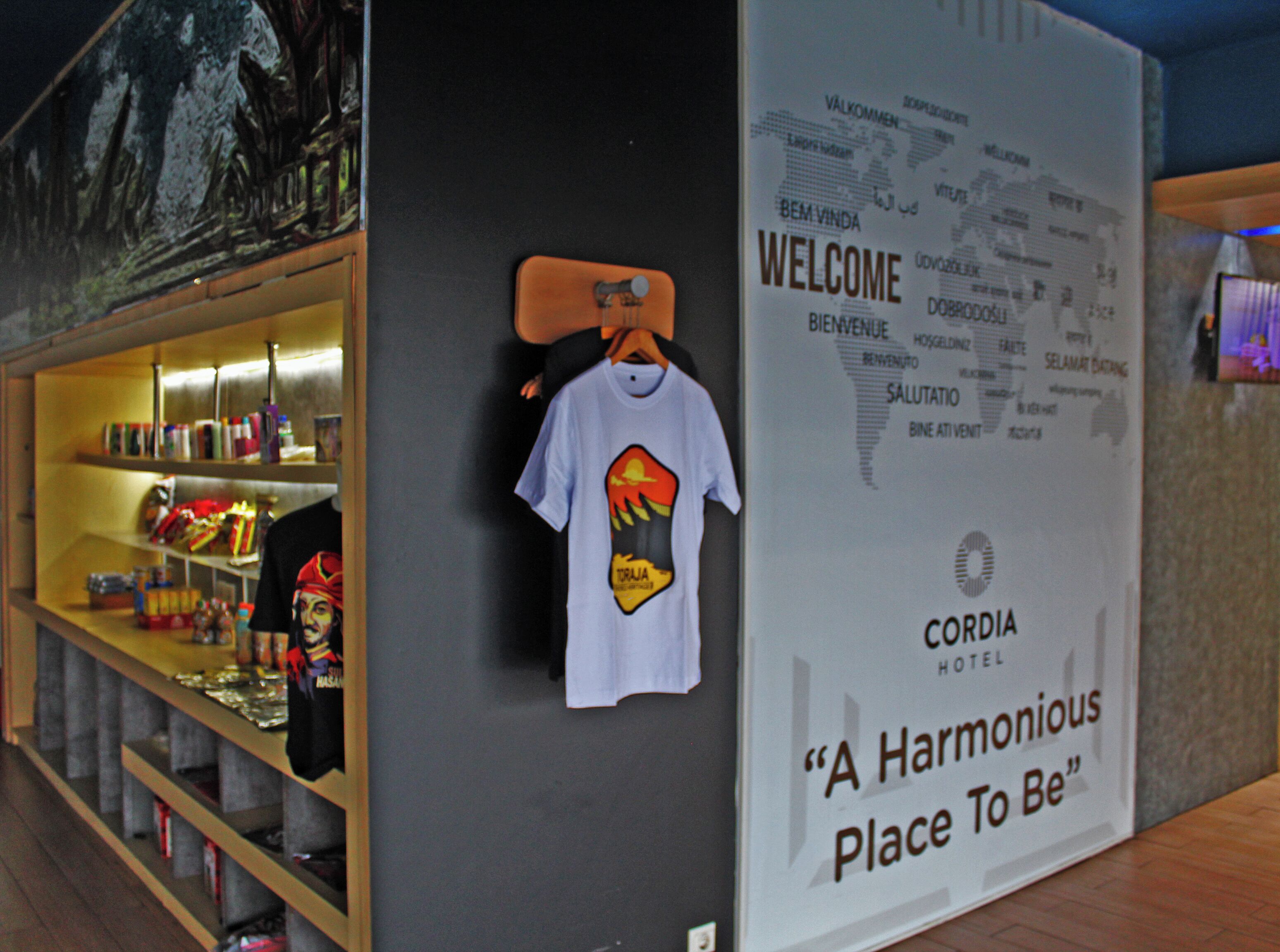 A welcome sign with a t-shirt on a hanger, a map, and a Cordia Hotel sign.