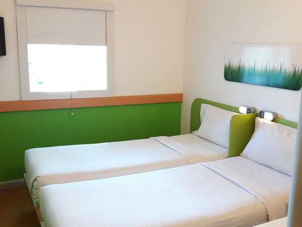 Una habitación con dos camas, una ventana y una obra de arte colgada en la pared.