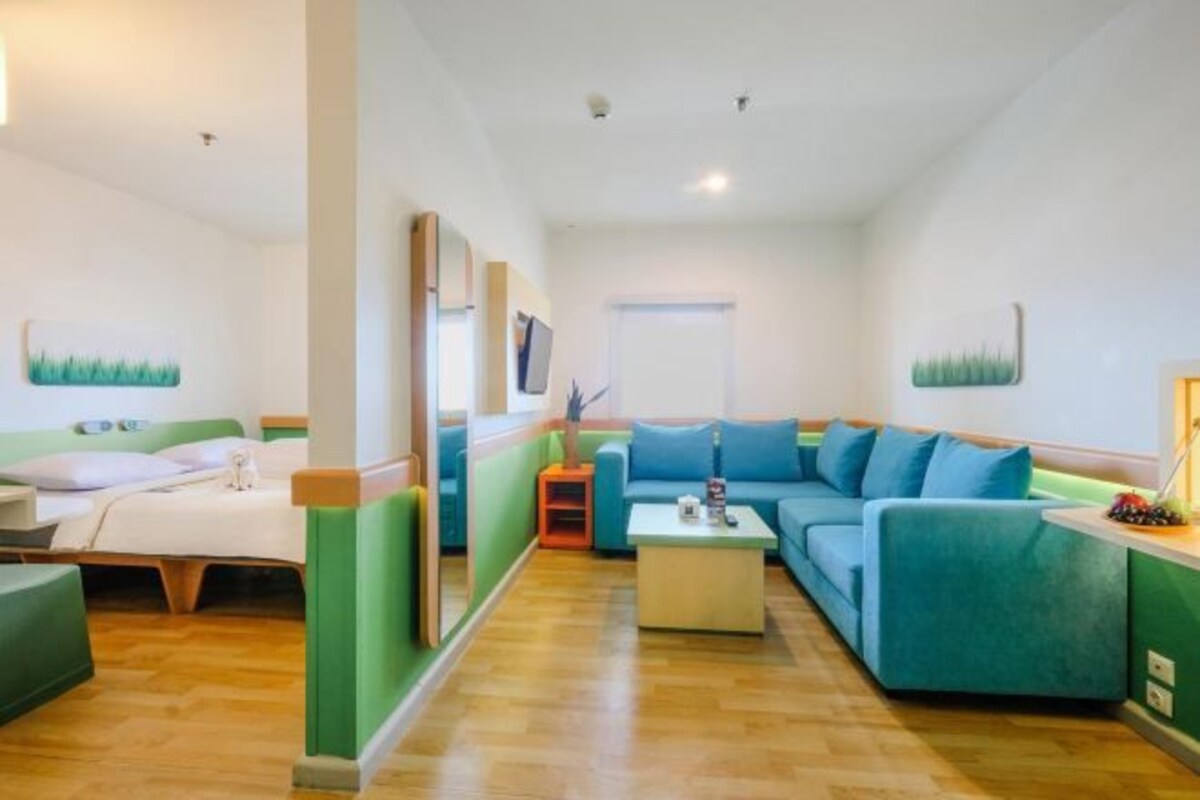 Een moderne hotelkamer met een bed, een bank, een salontafel en een televisie.