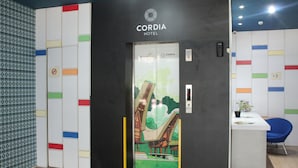 Un ascensor a l'Hotel Cordia amb un disseny de paret colorit i un senyal que indica zona per no fumar.