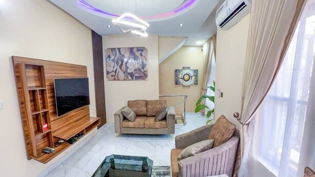 A modern living room with a flat-screen TV, a sofa, a chair, and a glass coffee table. - House - Sleeps 6 & private parking (Ikeja GRA)