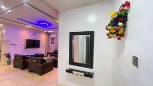 A modern living room with a flat-screen TV, comfortable seating, and a decorative flower arrangement on the wall. - House - Sleeps 6 & private parking (Ikeja GRA)