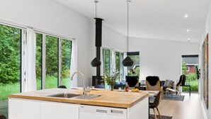 Une cuisine moderne dotée d’un îlot central, de grandes fenêtres et d’une cuisinière noire.
