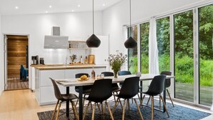 Une cuisine moderne avec des meubles blancs, un plan de travail en bois et un coin repas comprenant une table et des chaises.