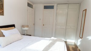 A bedroom with a bed, a nightstand, a lamp, and a wardrobe.